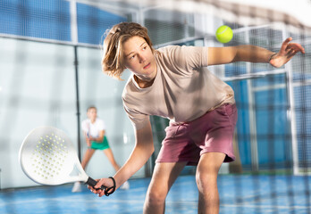 Portrait of a fifteen-year-old guy tennis player engaged in the popular sport of padel with a...