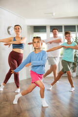 Parents together with their children learn how to dance salsa or boogie-woogie in a dance class