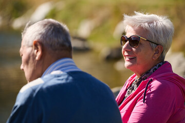 Obraz premium Elderly couple finding solace and joy as they rest on a park bench, engaged in heartfelt conversation, following a rejuvenating strol a testament to the enduring companionship and serene connection