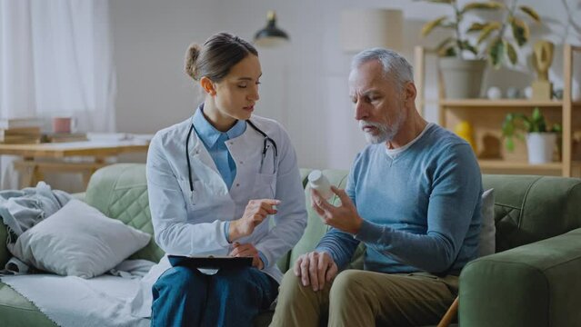 Woman doctor talking with senior man listening client and showing new pills to him