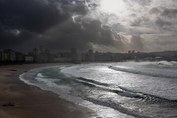 Sunlight Piercing Through Storm Clouds Over Beachfront City