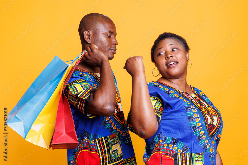 Wall mural african american man carrying bags with purchase while shopping in mall with woman. black couple in 