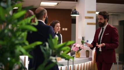 Hotel concierge offering luxury services to company professionals at resort, travelling on business trip for important meeting. Startup team doing check in at front desk reception.
