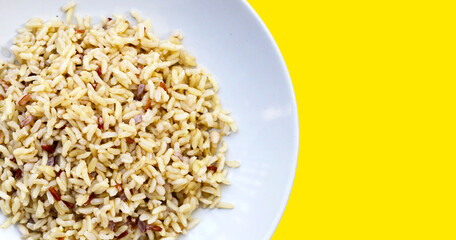 Cooked brown rice on yellow background.