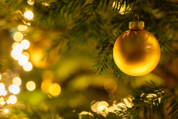 Golden christmas ball on christmas tree with lights