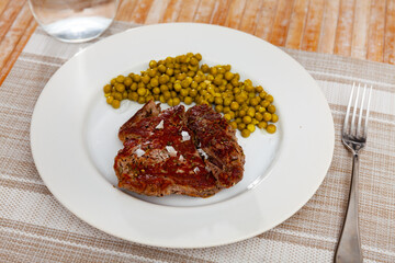 Popular all over the world dish of appetizing fried beef steak, a subject with green peas