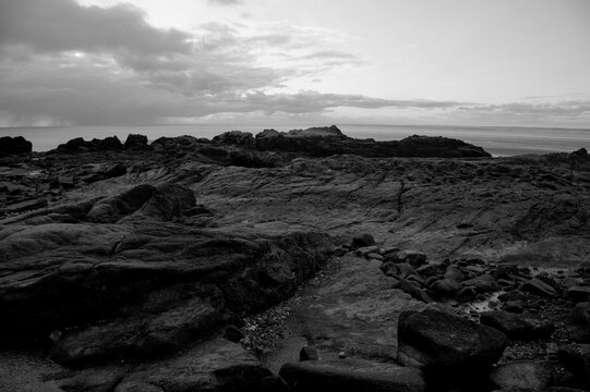 Black and white seascape of Morecambe Bay with dramatic atmospheric clouds casting shadows, capturing the tranquil beauty of the coastal scenery.