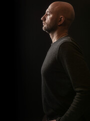 Portrait of man on a dark background. Male model with bald head and short beard in his 40s, slim...