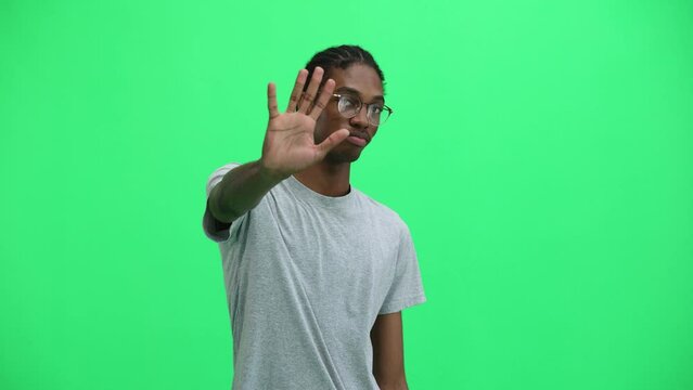 A man in a gray T-shirt, on a green background, close-up, shows a sign