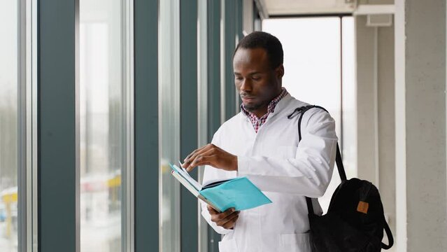 African american medical student reading book at university. Intern is preparing for the exam