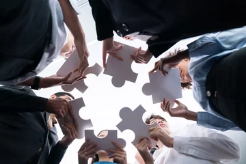 Foto op Canvas Below view of diverse corporate officer workers collaborate in office connecting puzzle pieces as partnership and teamwork concept. Unity and synergy in business idea by merging jigsaw puzzle. Concord © Summit Art Creations