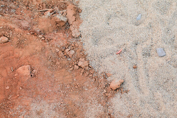 Red and gray gravel dirt road. Textures of ground with stones. Dry soil with crack for background. Close up Land surface.