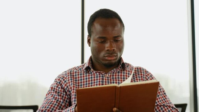 African American guy holding book, university student studying, learning language