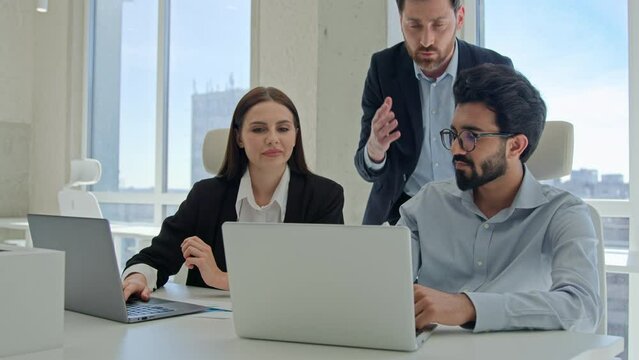 Diverse team corporate coworkers working laptops in office male business coach mentor boss businessman helping employees with computer work training new workers help interns check explain data project