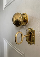 Antique door lock. Golden door handle with antique gold-engraved crest. Ancient lock with key. Old metal key in the keyhole.