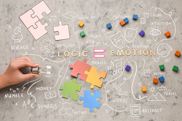 Hand with light bulb, words LOGIC, EMOTION, cubes and puzzle pieces on grunge background