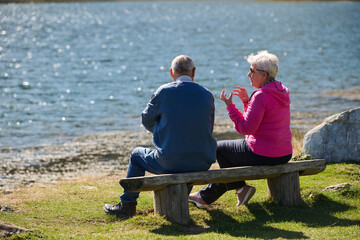 Elderly couple finding solace and joy as they rest on a park bench, engaged in heartfelt conversation, following a rejuvenating strol a testament to the enduring companionship and serene connection