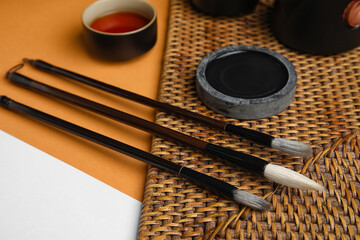 Brushes, ink and cup of tea on color background, closeup. International Haiku Poetry Day