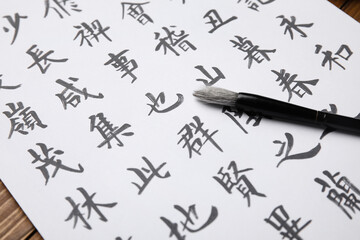 Paper sheet with Asian hieroglyphs and brush, closeup. International Haiku Poetry Day