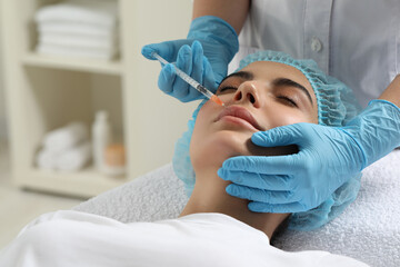 Doctor giving lips injection to young woman in clinic. Cosmetic surgery