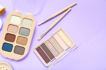 Eyeshadows with brushes on lilac background