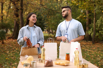Volunteers packing food products at table in park