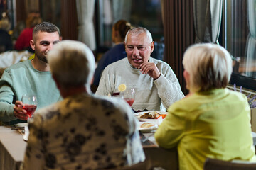 A group of family friends, comprising a young grandson and older individuals, share a delightful dinner in a modern restaurant, exemplifying the concept of healthy aging through intergenerational
