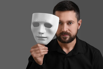 Multiple personality concept. Man with mask on grey background