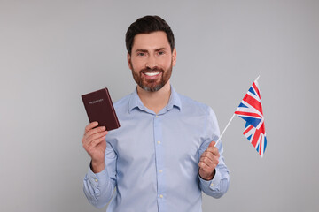 Immigration. Happy man with passport and flag of United Kingdom on gray background