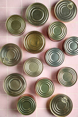 Many tin cans with fish on pink tiled table