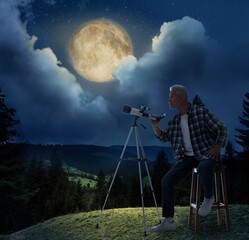 Senior astronomer with telescope on hill at full moon night