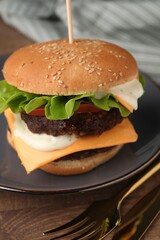 Tasty cheeseburger with patties and cutlery on wooden table, closeup