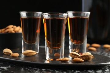 Glasses with tasty amaretto liqueur and almonds served on table, closeup
