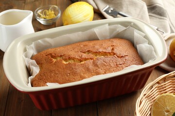 Tasty lemon cake in baking dish on wooden table, closeup