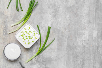 Bowls of tasty sour cream with green onion on grunge background