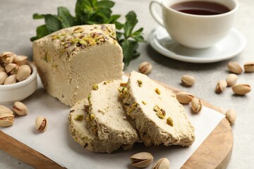 Tasty halva with pistachios served on grey table, closeup