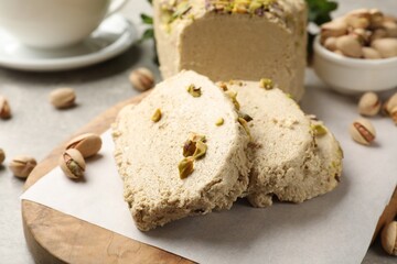 Tasty halva with pistachios on light grey table, closeup