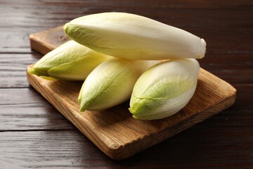 Raw ripe chicories on wooden table, closeup