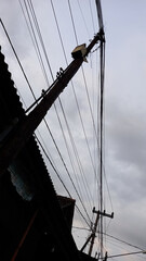Obraz premium Dozens of electrical cables are tangled in a mess at the top of an electricity pole.