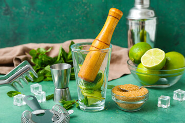 Glass with mortar and ingredients for preparing mojito on table