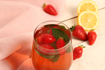 Glass of tasty strawberry juice on white table