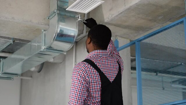 Professional Black Heating and Cooling Technician Worker Finishing Newly Assembled Air Vent Shaft. Air Climate Control and Filtering in Commercial Building