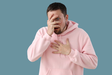 Young man having panic attack on blue background