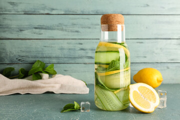 Bottle of lemonade with cucumber and mint on blue table