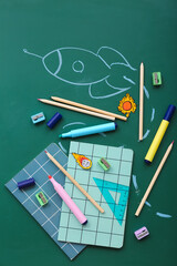 Creative composition with drawn rocket and different stationery on green chalkboard