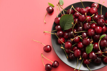 Plate with sweet cherries on red background