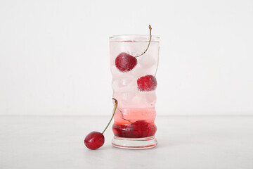 Glass of tasty cherry lemonade on white background