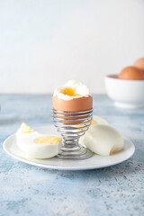 Holder with boiled chicken egg on blue table