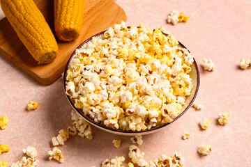 Bowl with tasty popcorn on pink background