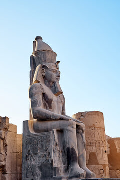 Seated statue of Ramesses II by the First pylon of the Luxor Temple, Egypt. Columns and statues of the Luxor temple main entrance, first pylon, Egypt
